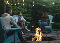 Freunde sitzen um ein Feuer herum und rösten Marshmallows auf Adirondack-Stühlen.