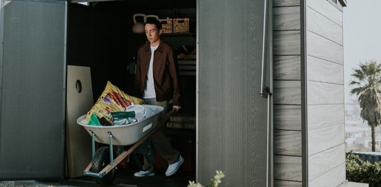 man carrying things out of a shed