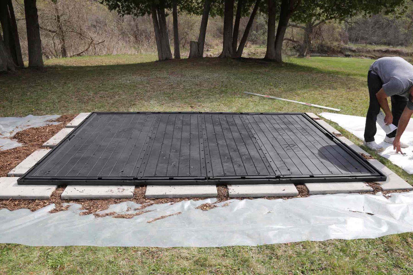 man assembling a shed floor on top of a solid foundation