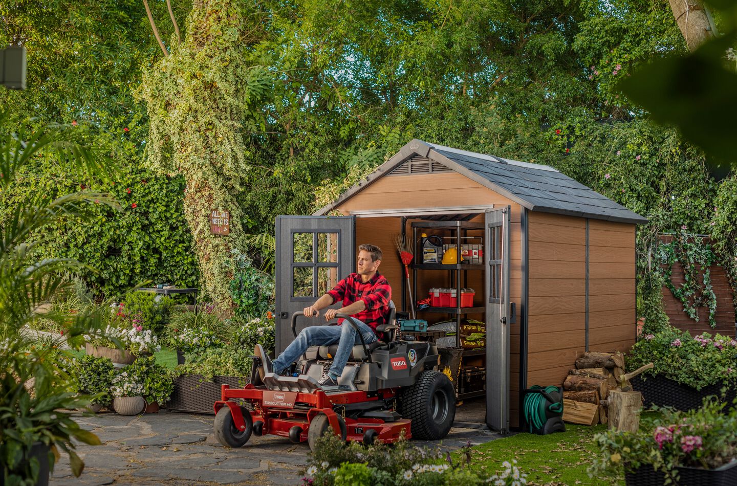 Man driving his lawn mover out of his large backyard shed