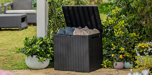 Small deck box in backyard holding outdoor furniture cushions