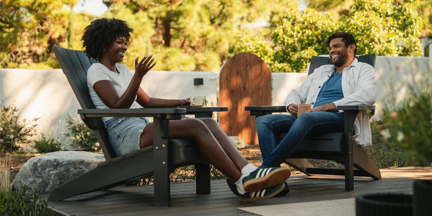 man and woman talking outside sitting on adirondack chairs