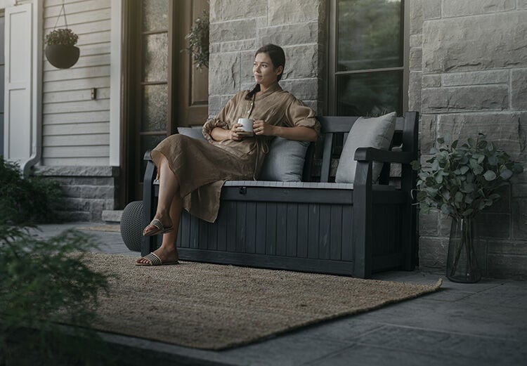 Woman enjoying a cup of coffee while sitting on a storage bench