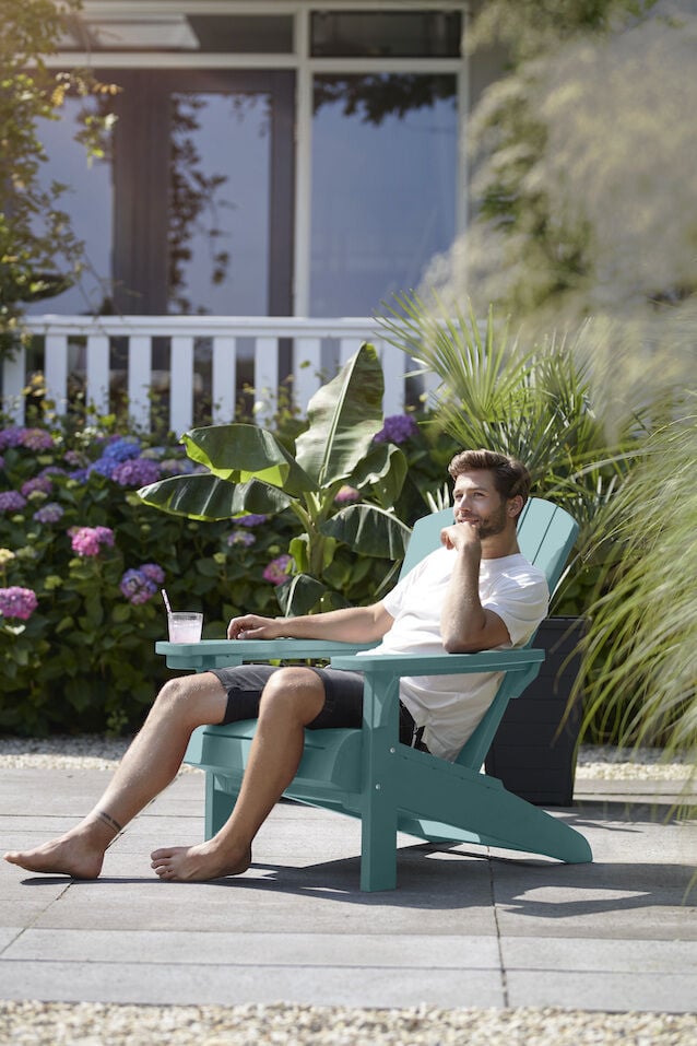 Man relaxing with a drink and sitting in a Adirondack chair