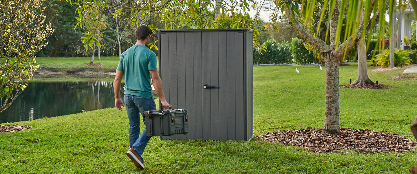 Man walking to a shed with a toolbox