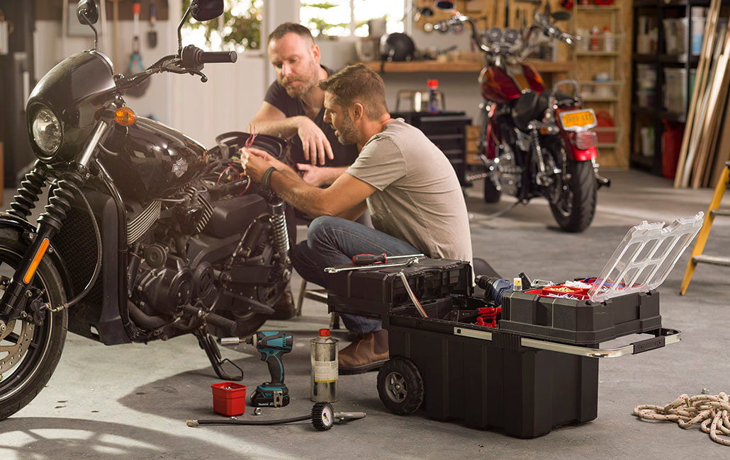 man working on a bicycle with a toolbox next to him