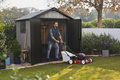 Man pushing a lawn mover out of a backyard shed