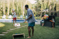 two men are playing cornhole in their backyard