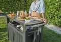 Man and woman grab a drink together form their Keter Patio Cooler while outside on their patio during a party  