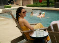 woman sitting in her keter adirondack while her kids splash in the pool