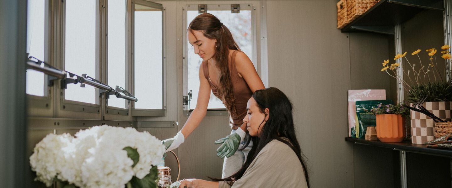 Two women potting plants inside keter potting shed