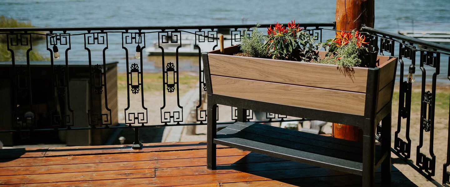 Woman planting herbs in a grey elevated garden bed