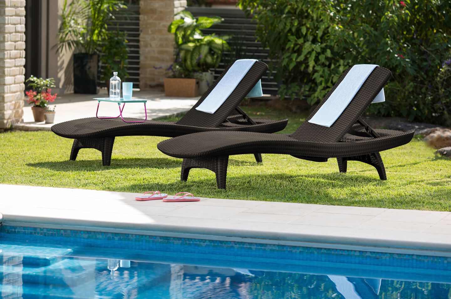 Pair of brown sun loungers next to the pool