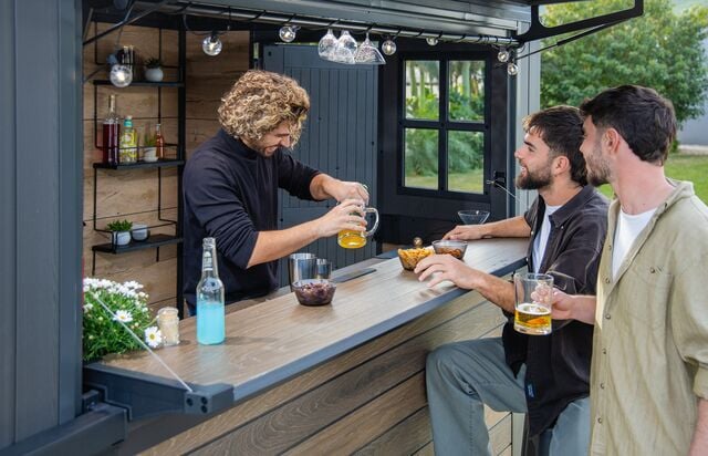 friends making drinks outside in a bar shed