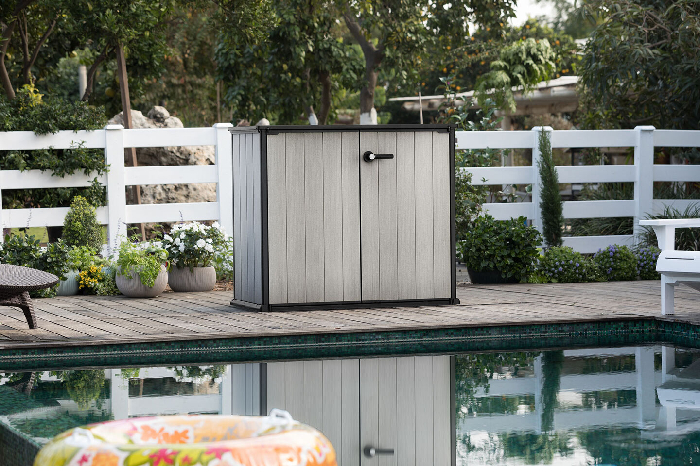 Small grey storage shed next to a pool