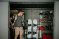 man in a shed filled with outdoor winter equipment