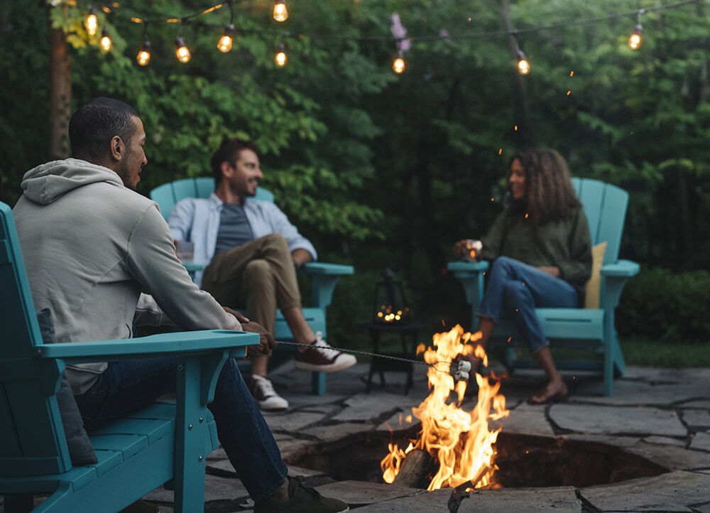 Group of friends sitting on adirondack chairs around a fire pit