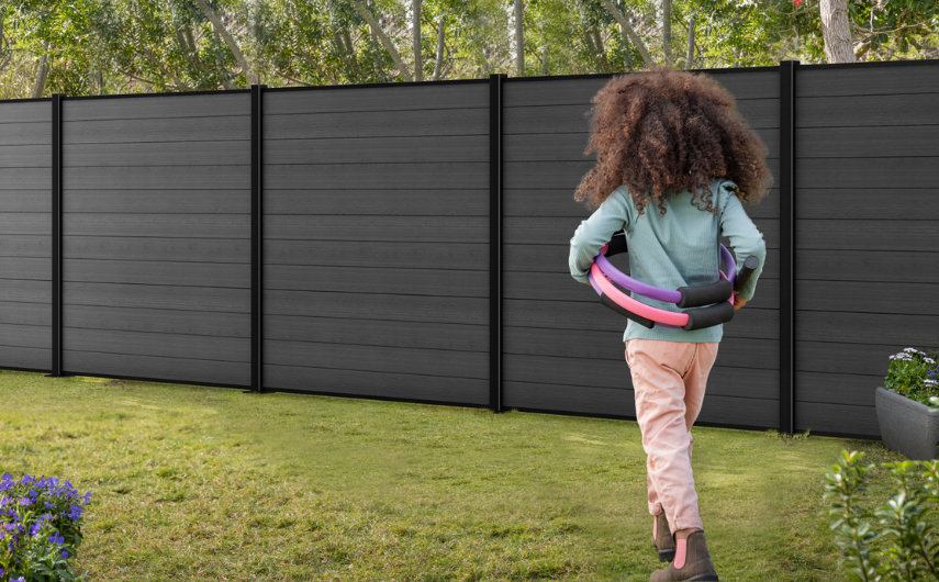 Fillette jouant devant une cloture grise