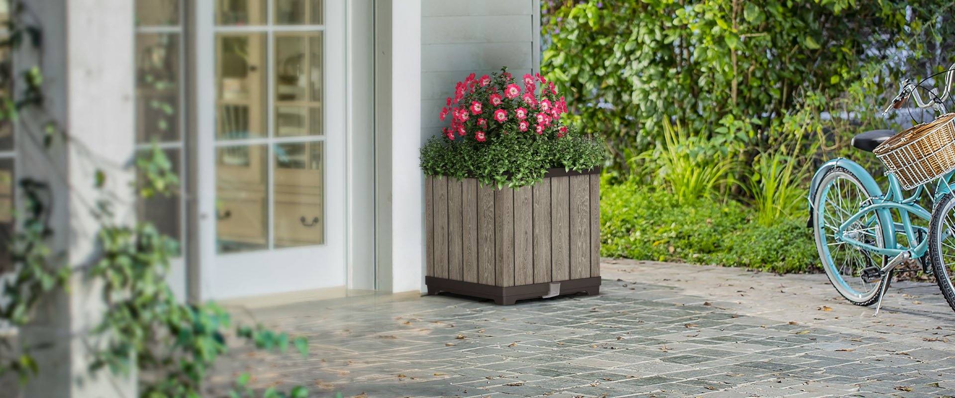 Keter Signature Planter on a garden patio with pink flowers