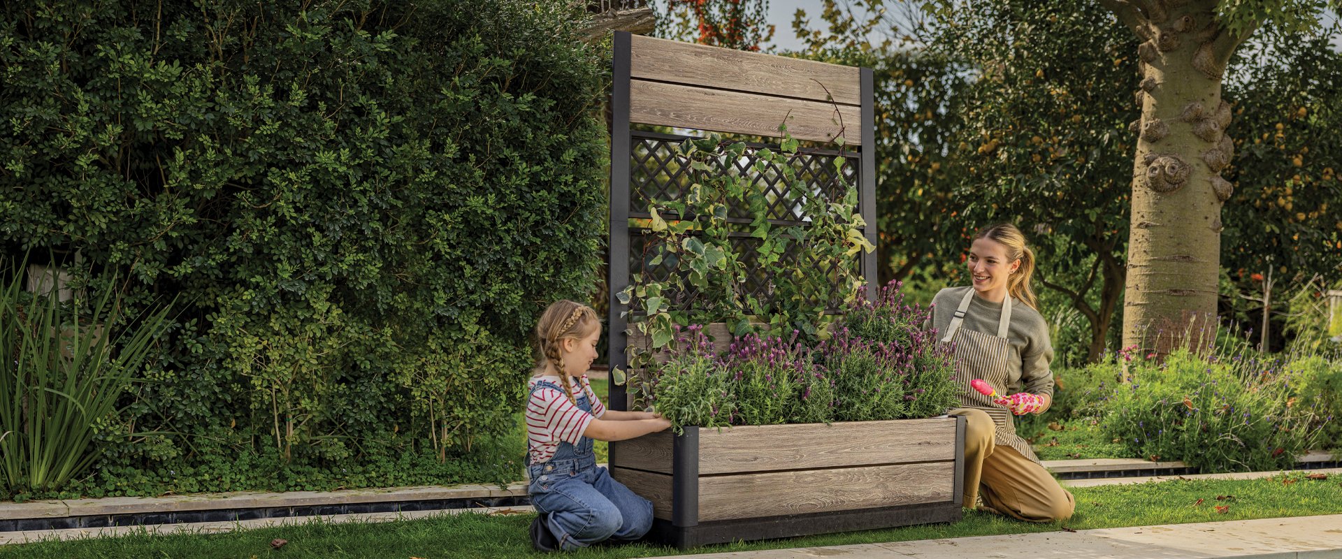 Keter Signature Planter on a garden patio with pink flowers