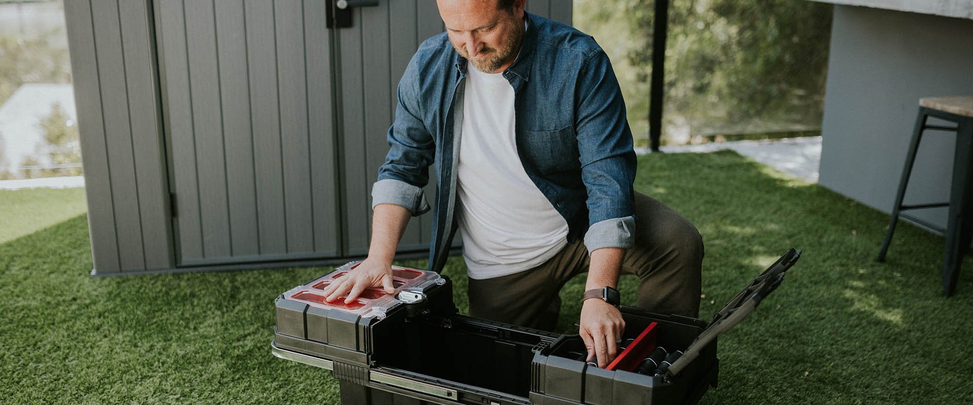 man with keter portable tool box masterloader in backyard